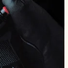 Black leather glove gripping steering wheel